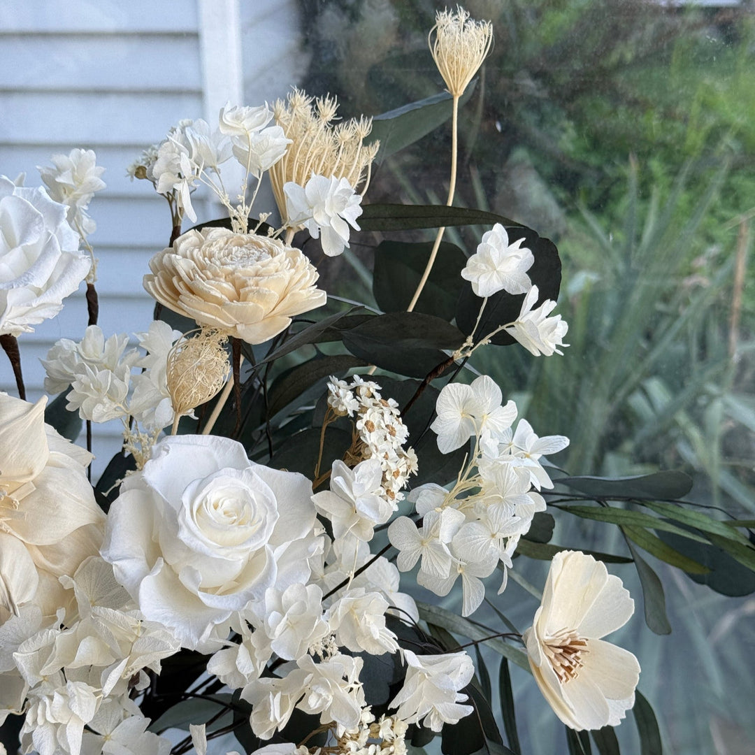 Detailed view of ivory and cream preserved florals with eucalyptus leaves
