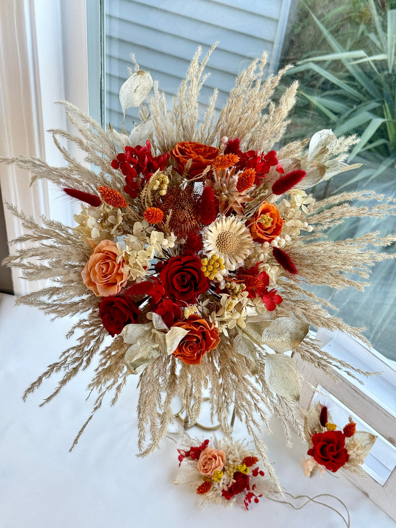Preserved bohemian bridal bouquet displayed with matching floral accessories in warm autumn-inspired colors