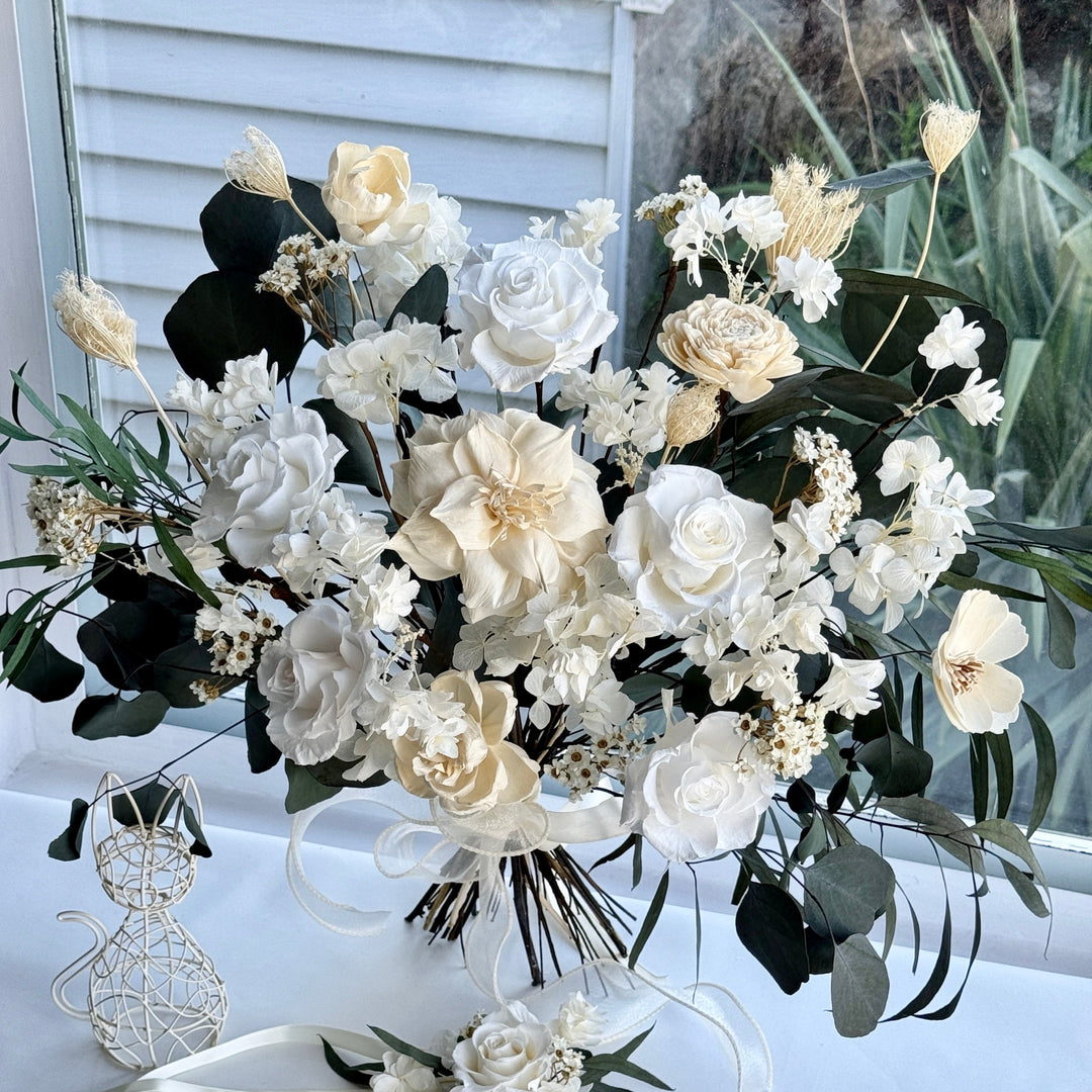 Ethereal ivory preserved bridal bouquet with soft white roses, hydrangeas, and eucalyptus foliage