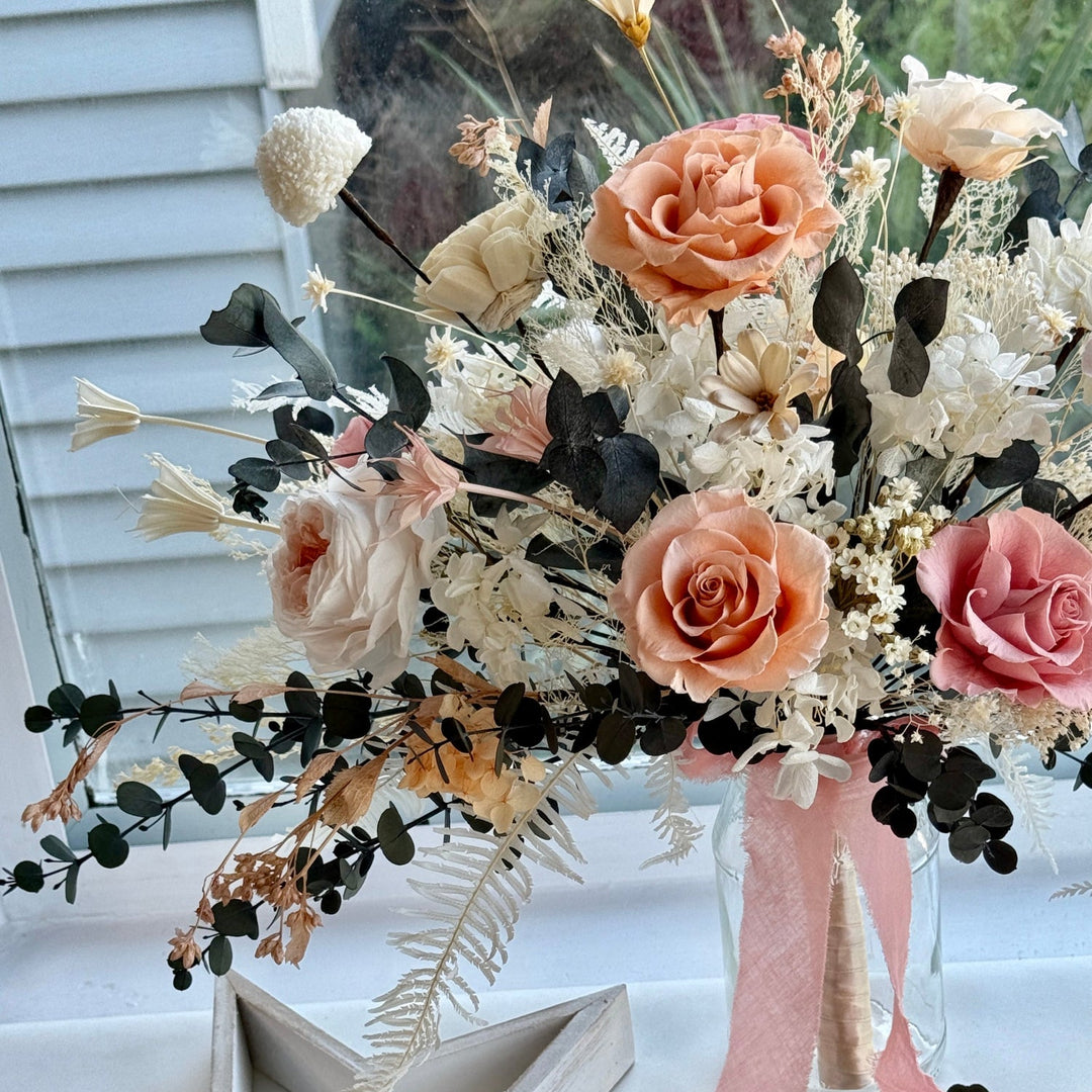 Luxury preserved flower bridal bouquet in coral, blush, and creamy ivory tones with natural dried textures