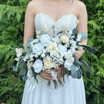 Load image into Gallery viewer, Bride holding an ethereal ivory preserved bridal bouquet with cream roses and natural greenery